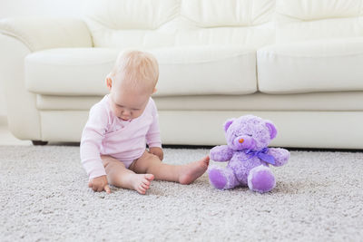 Cute baby girl sitting with toy at home