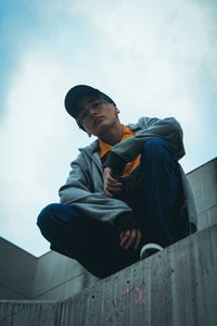 Low angle view of man sitting against sky