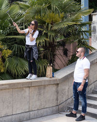 Full length of smiling young woman standing on palm tree