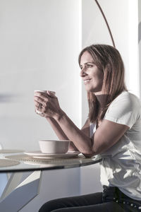 Woman drinking coffee at table in cafe