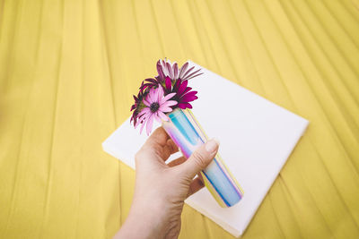 Cropped hand of woman holding flowers on table