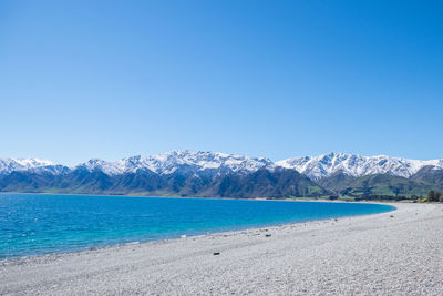 Scenic view of sea and mountains against clear blue sky