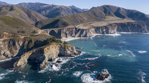 Scenic view of rocks in sea by mountains