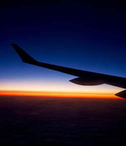 Airplane wing against sky during sunset