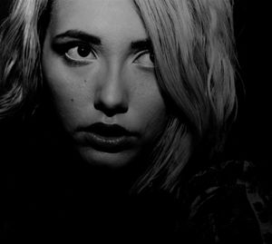 Close-up portrait of young woman against black background