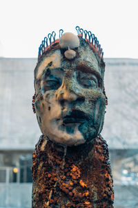 Close-up portrait of man with sculpture against sky