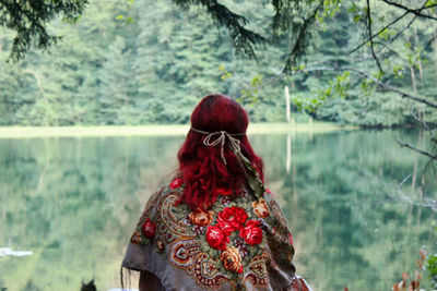 Girl with red hair sitting near lake