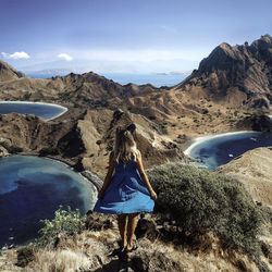 Rear view of woman looking at mountains against sky