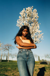 Young woman standing on field against sky