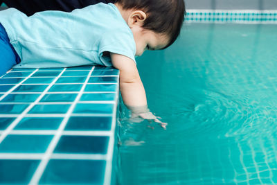 Side view of baby girl sitting by swimming pool