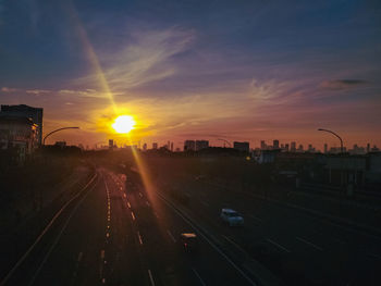 Cars on street against sky during sunset