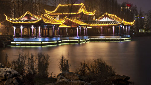 Illuminated building by lake at night
