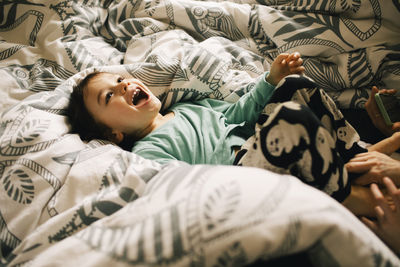 High angle view of happy boy lying on bed at home