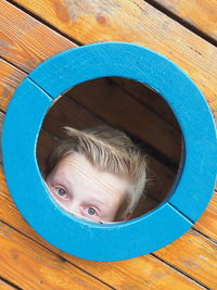 Close-up of boy peeking out of window