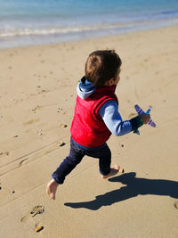 Full length of boy running on sand at beach