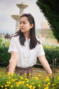 Portrait of young woman standing against plants