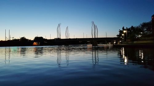 Metallic structure reflection in lake against sky