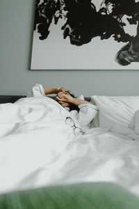 Low section of man relaxing on bed at home