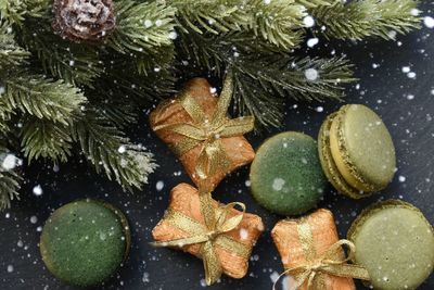 High angle view of christmas presents by pine needles and macaroons on table