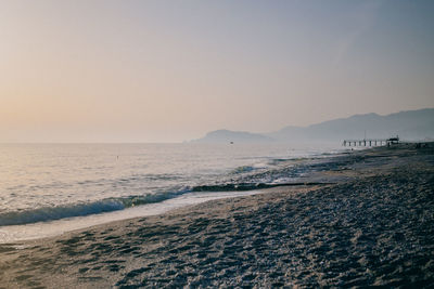 Scenic view of beach against clear sky during sunset