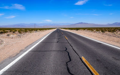 Asphalt road leading through steaming hot landscape of death valley national park