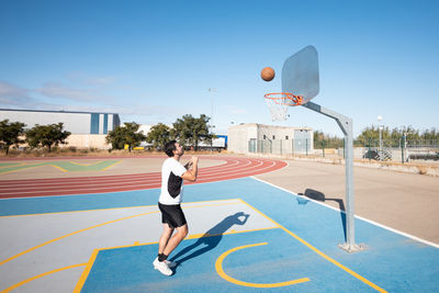 Man playing with basketball hoop against sky