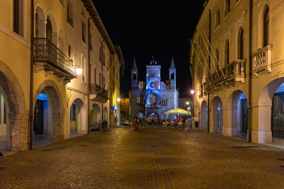 Illuminated street amidst buildings in city at night