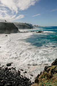 Panorama of a rocky ocean coastline with a city view behind, tenerife