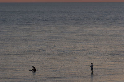 High angle view of silhouette people in sea