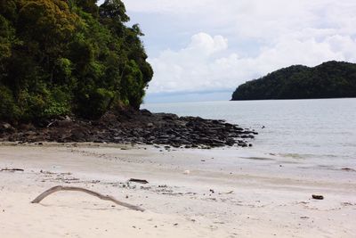 View of calm beach against cloudy sky