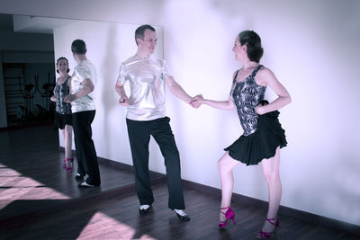 Full length of couple dancing against mirror
