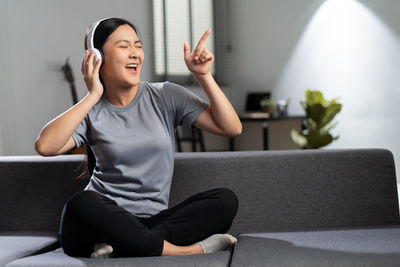 Young woman using mobile phone while sitting at home