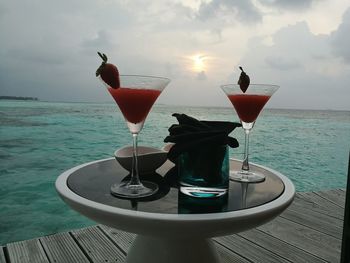 Close-up of drink on sea against sky