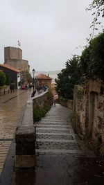 Footpath amidst buildings in city against sky