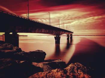 Bridge over sea against sky during sunset