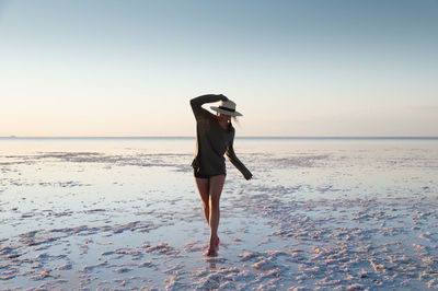 Charming romantic woman serenely walks through the colorful landscape of salt marshes on a pink lake