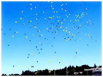 Low angle view of balloons flying against blue sky