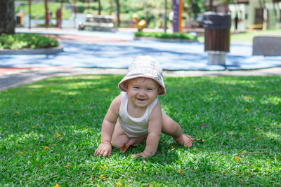 Lifestyle portrait of smiling baby girl. child tries to crawl on grass in park. 