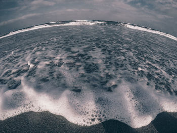 Aerial view of sea against cloudy sky