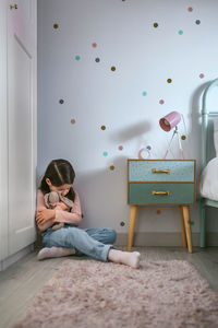 Girl sitting with stuff toy in bedroom