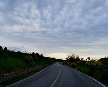 Road passing through landscape against cloudy sky