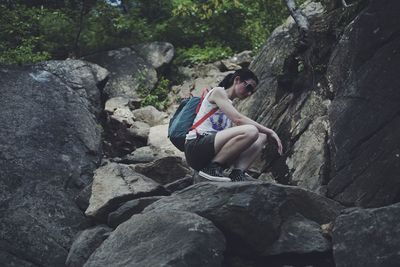 Low angle view of woman crouching on rock