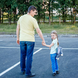 Father and daughter standing on road in city