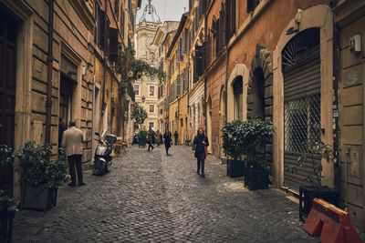 People walking on street amidst buildings in city