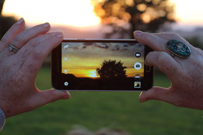 Cropped image of woman photographing through smart phone