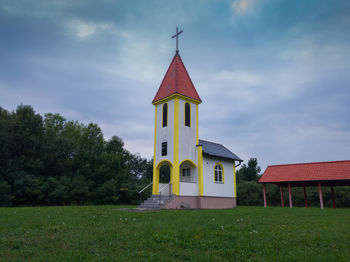 Traditional windmill by building against sky
