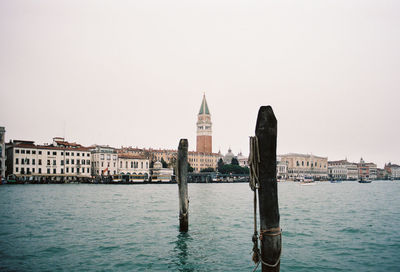 Wooden post on river by buildings