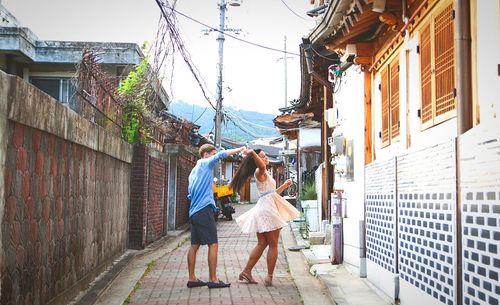 Full length of couple dancing on footpath