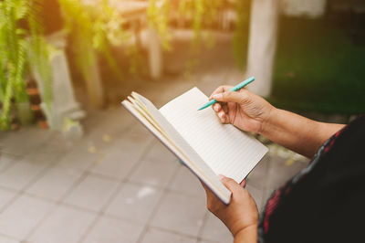 Midsection of woman writing in diary