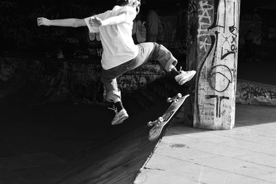 Low section of man skateboarding on street